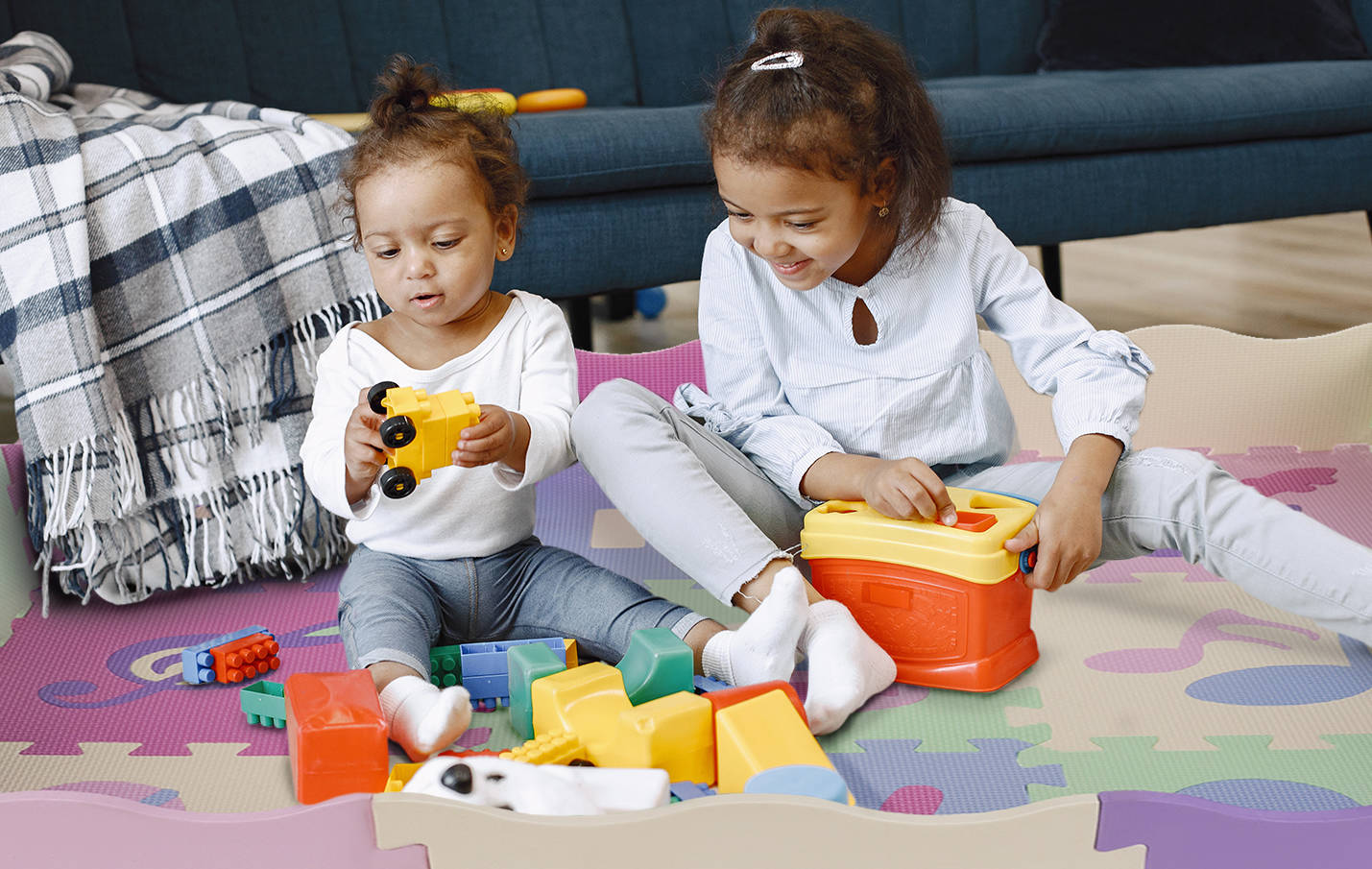 Cute little girls playing with toys on the floor near the couch