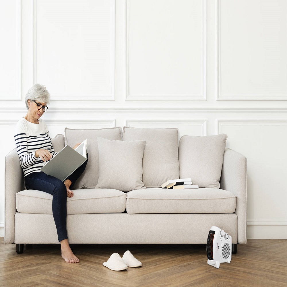 Senior woman reading a book on the sofa in a Scandinavian decor